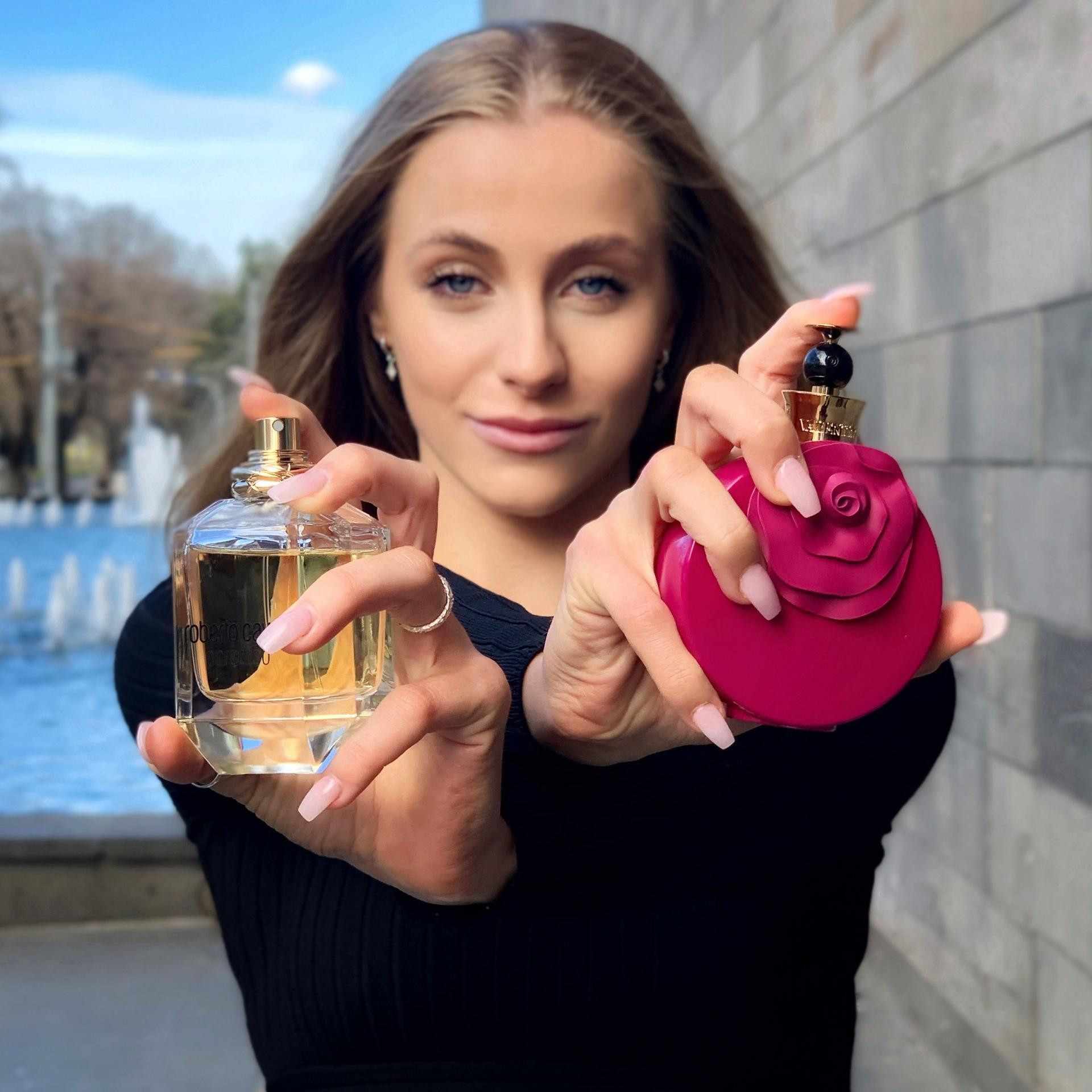 A woman holding two perfumes in her hands