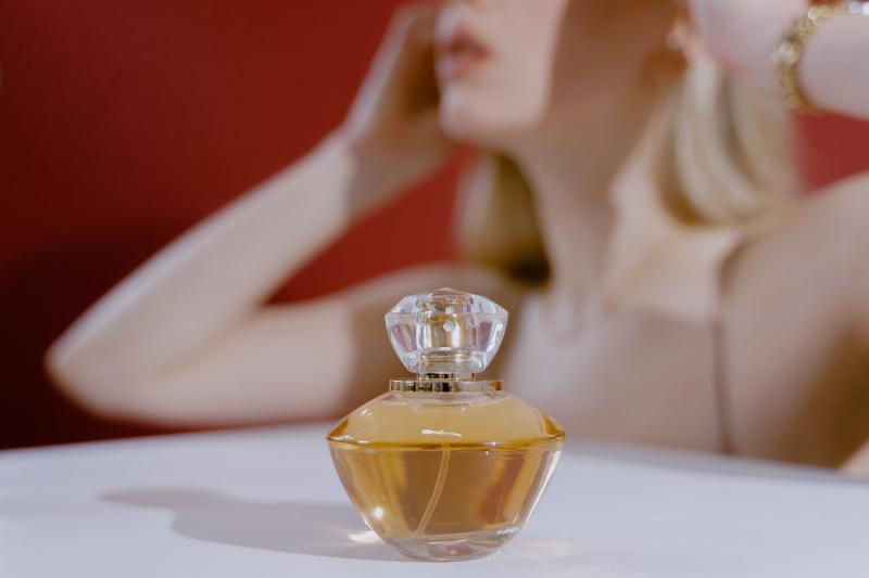 A perfume bottle on the table with a confused woman in the background
